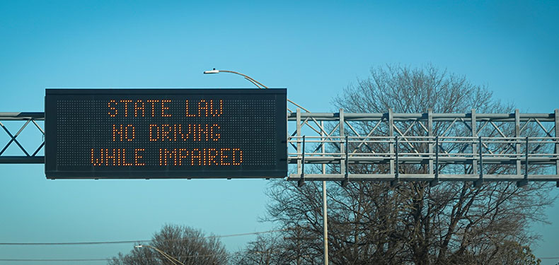 An electronic traffic sign that reads 'State Law No Driving While Impaired'.