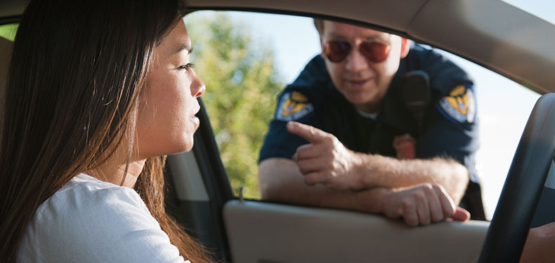 An image of a female driver pulled over and being spoken to by a police officer.